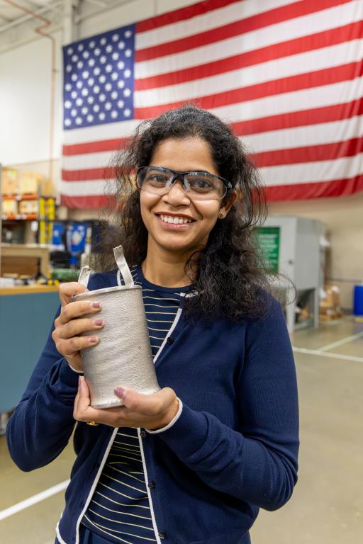 ORNL scientist Vanshika Singh holding a solid nickel component produced with a leak-free HIP can
