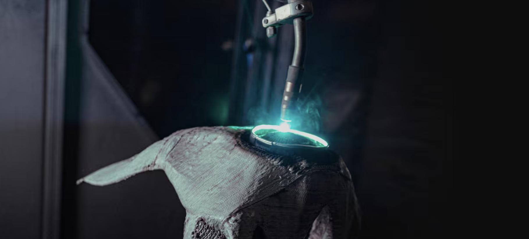 Close-up of an MX3D robotic arm depositing molten metal during a wire-arc additive manufacturing (WAAM) print