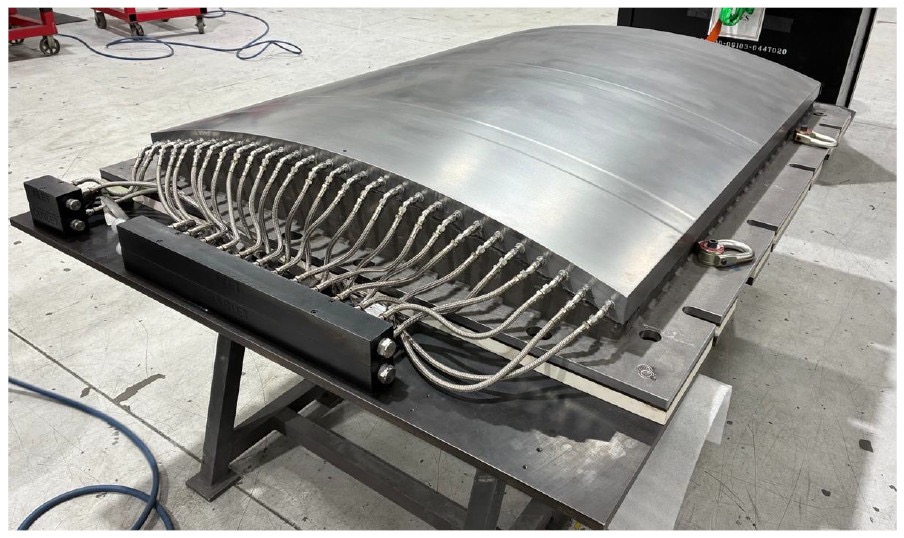 Curved metal aircraft mold on a fabrication table after finishing