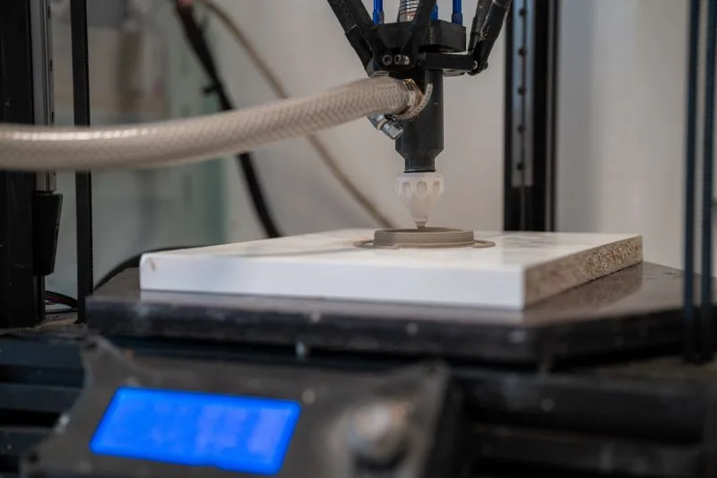 Close-up of clay being deposited in layers by a ceramic extruder