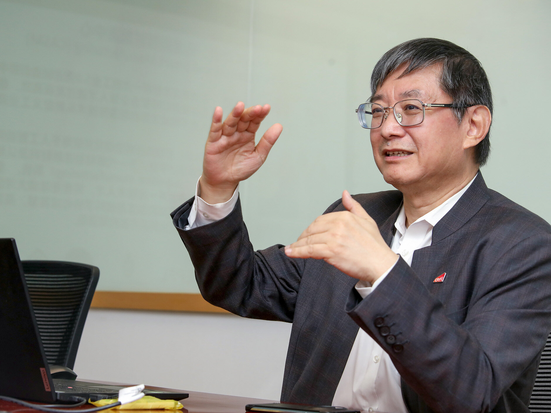 Lu Jian speaking and gesturing beside a laptop