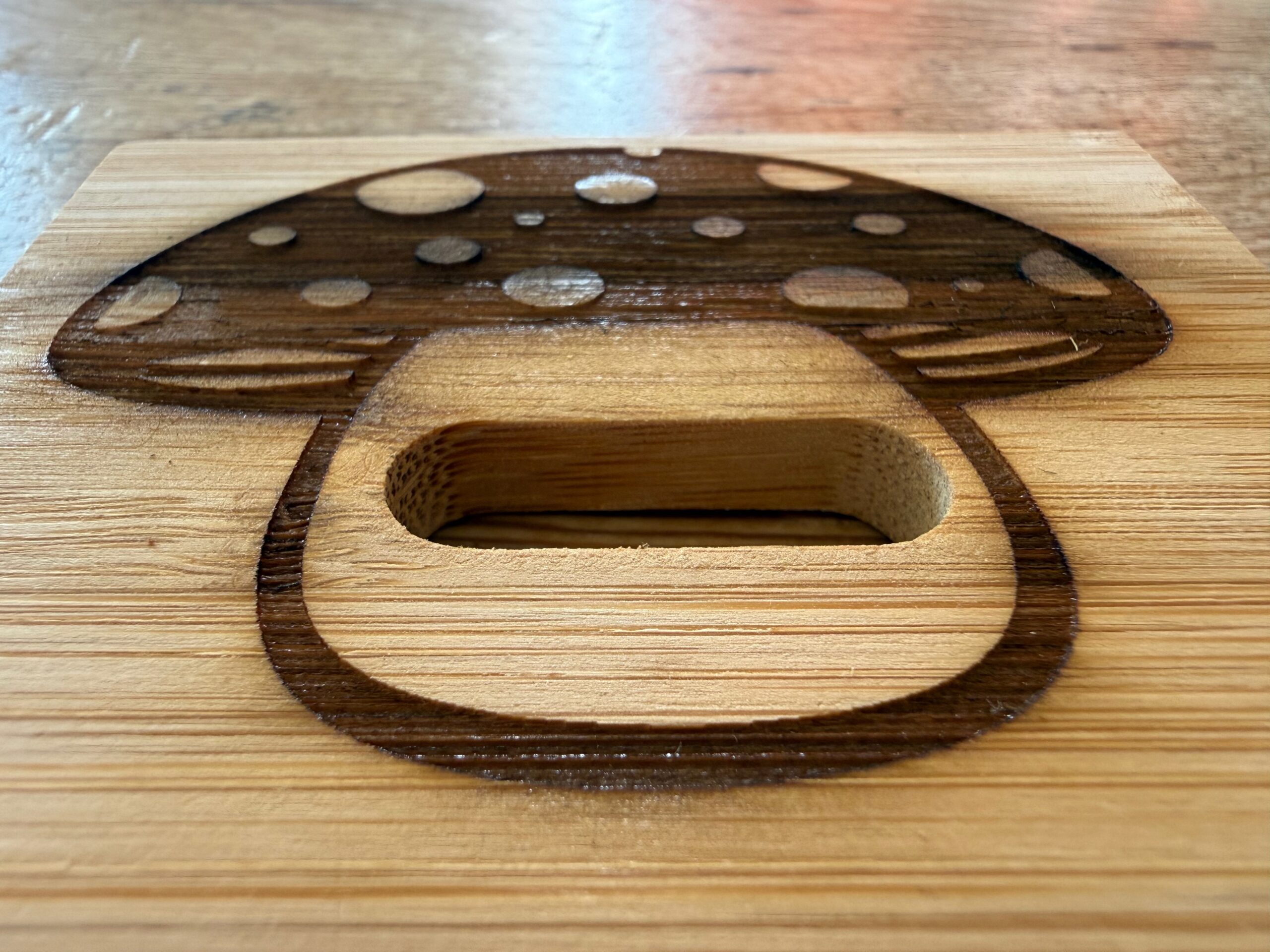 Close-up of the mushroom engraved into bamboo at a low angle, showing the recessed relief of the cap