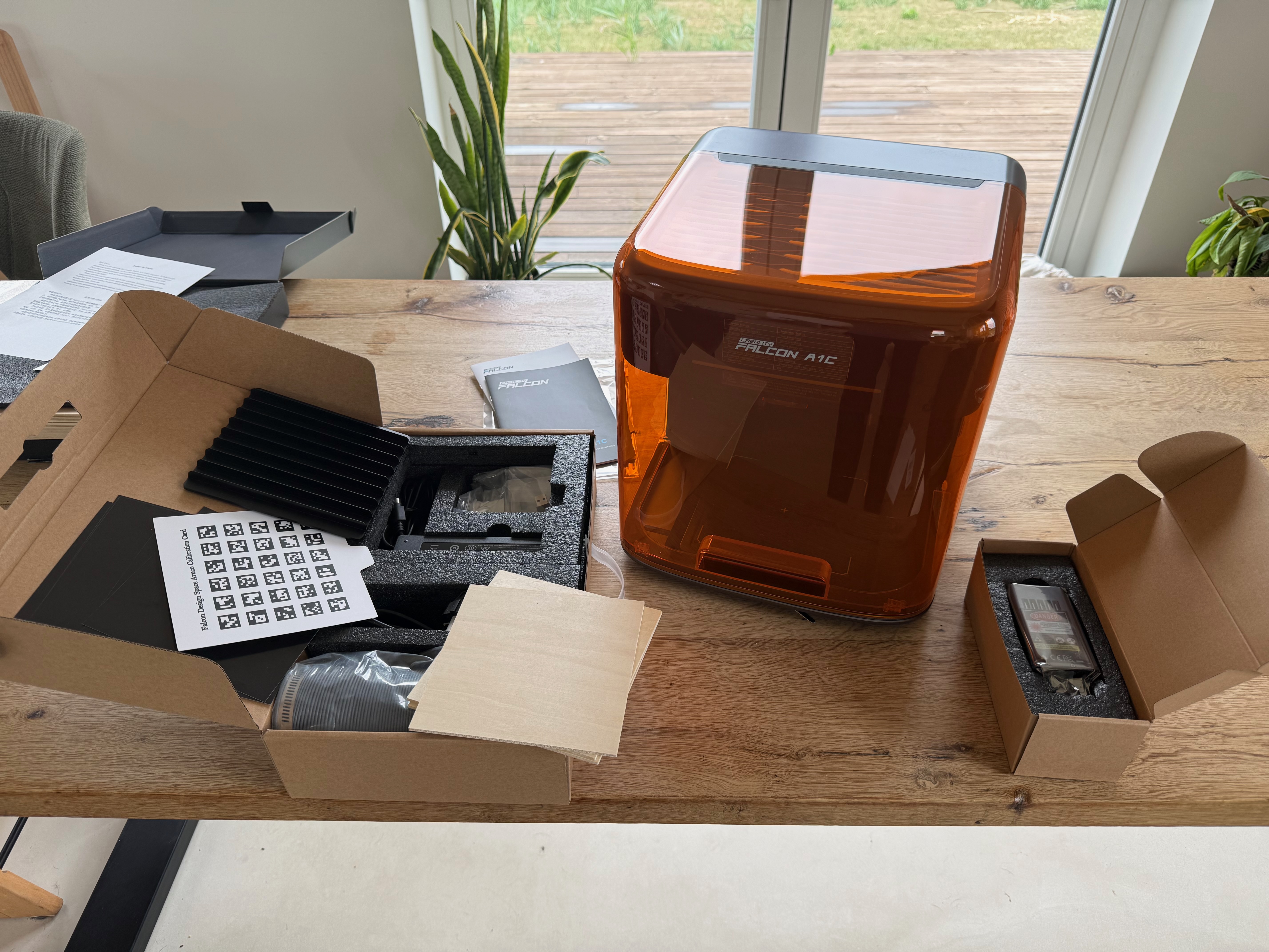 Everything that came in the Creality Falcon A1C box laid out on a table, with the machine behind