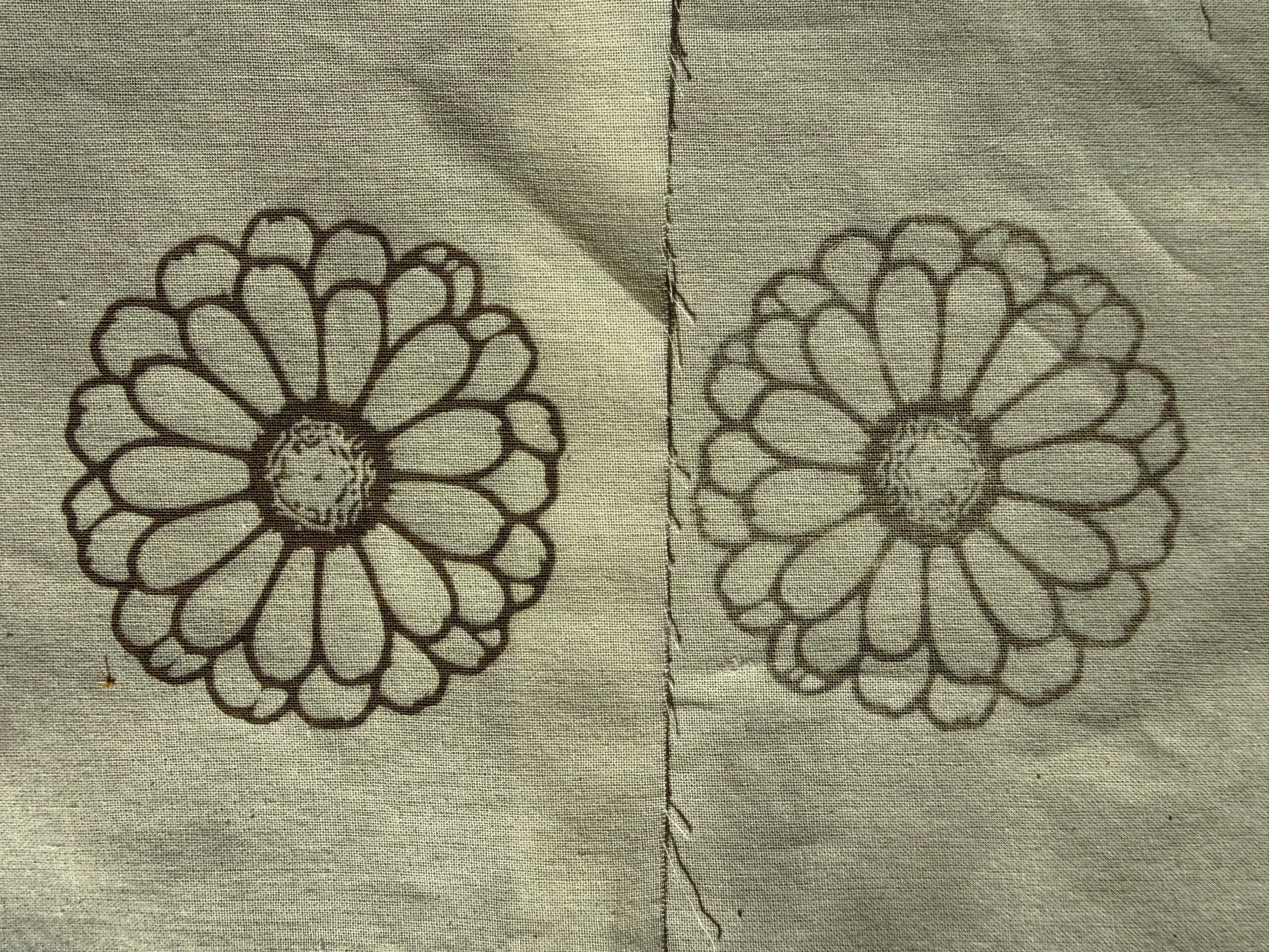 Two pieces of cotton cloth each with a flower engraved on it, the left one darker