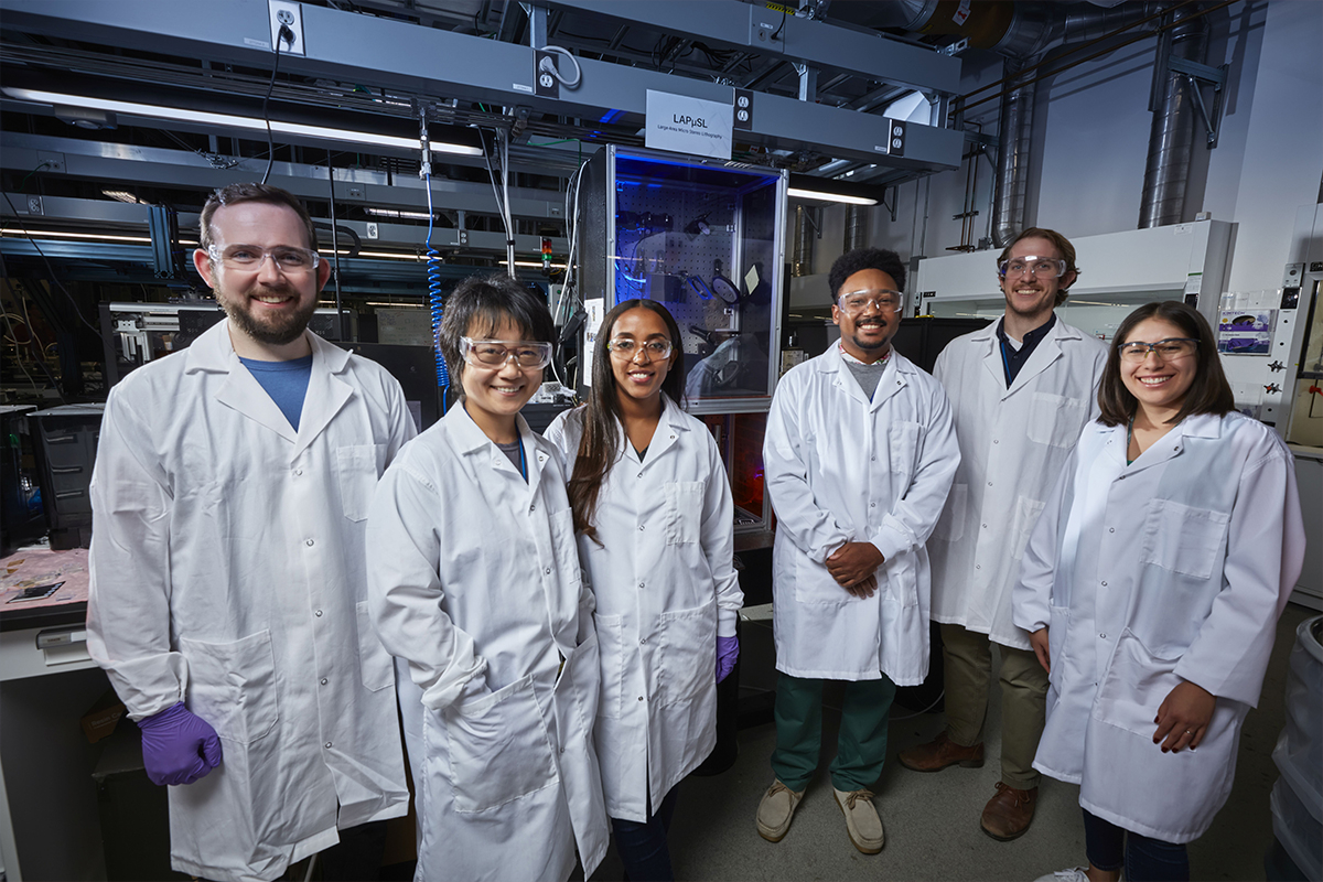 Six LLNL researchers in lab coats standing in a printing laboratory
