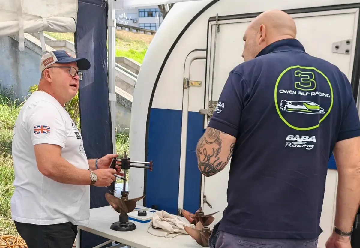 Dave Harwood checking a five-bladed 3D printed metal propeller on a measuring stand in the pits, with Rob Bowyer beside him
