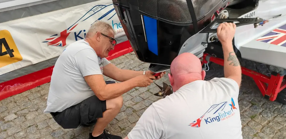 Ian Blacker crouching beside his UIM F2 boat in the pits, fitting a five-bladed 3D printed metal propeller