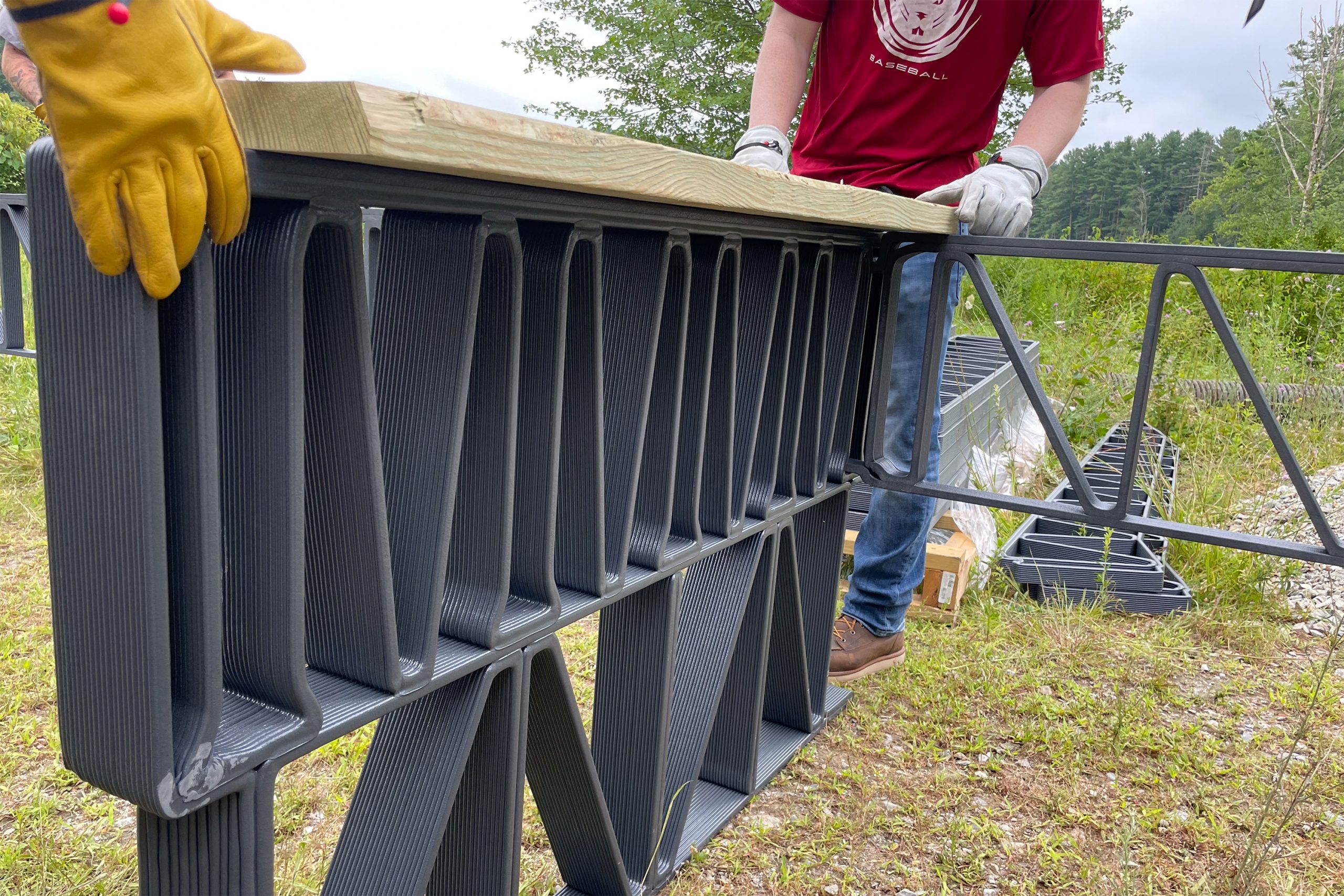 Layered 3D-printed composite trusses with a wood deck being placed on top