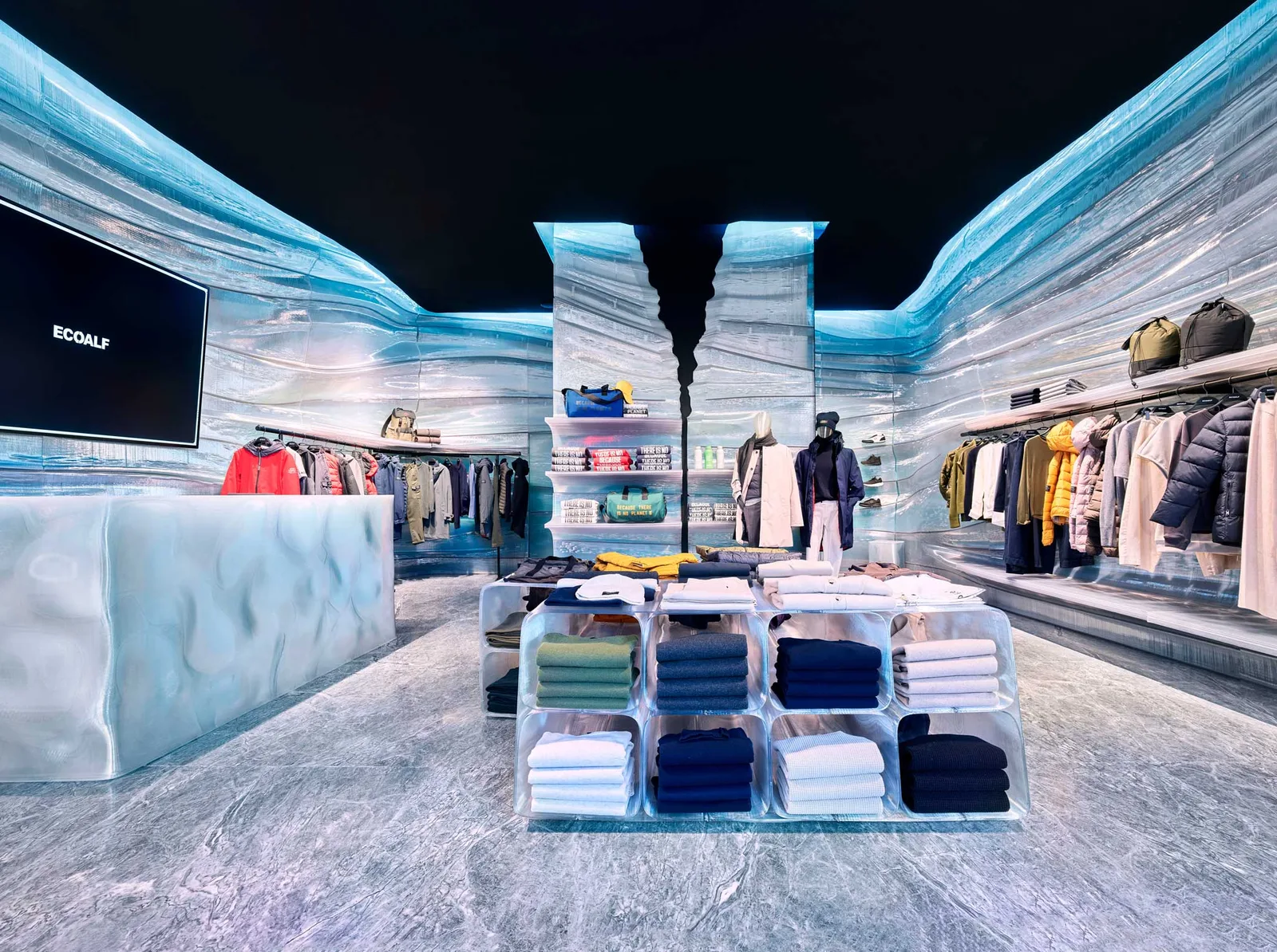 Store interior with pale blue printed walls, shelves and display tables holding clothing