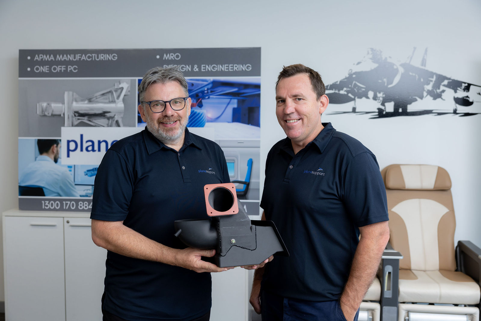Plane Support team members with a 214B cabin duct made on a 3D printer