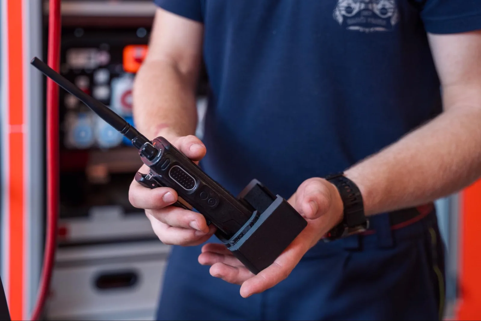 Firefighter holding a handheld radio fitted into a black 3D printed holder
