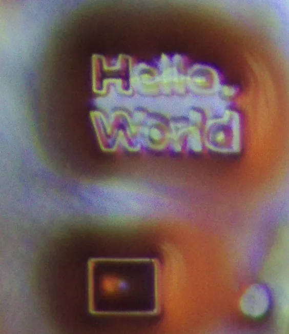 Hello World text and a small square cured in resin, seen under a microscope