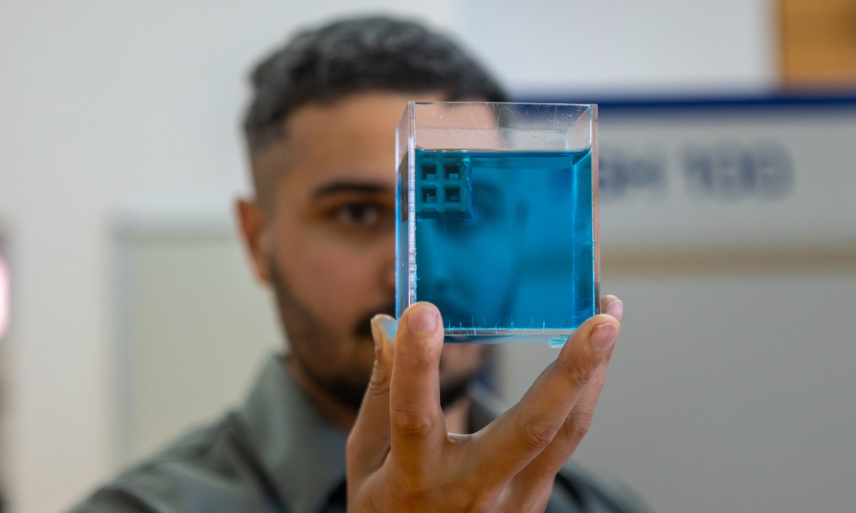 Jordan Noronha holding a 3D printed floating titanium sample