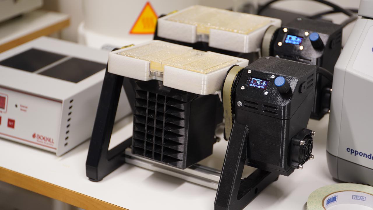 Black 3D-printed laboratory instruments with small screens sitting on a bench