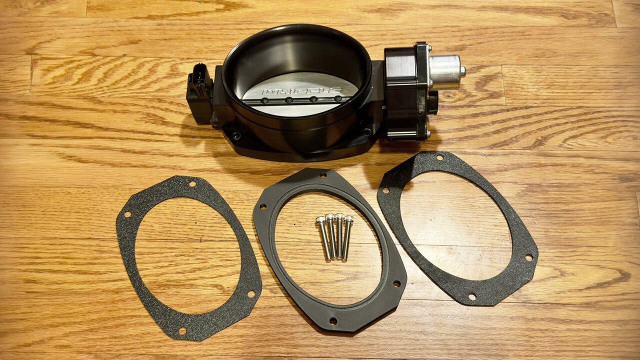 The black 132 mm Whipple throttle body with gaskets and hardware for the custom spacer kit project